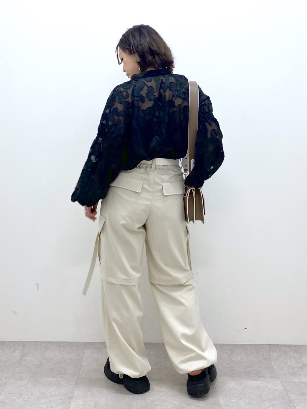 グレー系のパンツ、ブラック系のサンダル、ブラウン系のショルダーバッグを着用したレディースの春コーディネートの3枚目の写真