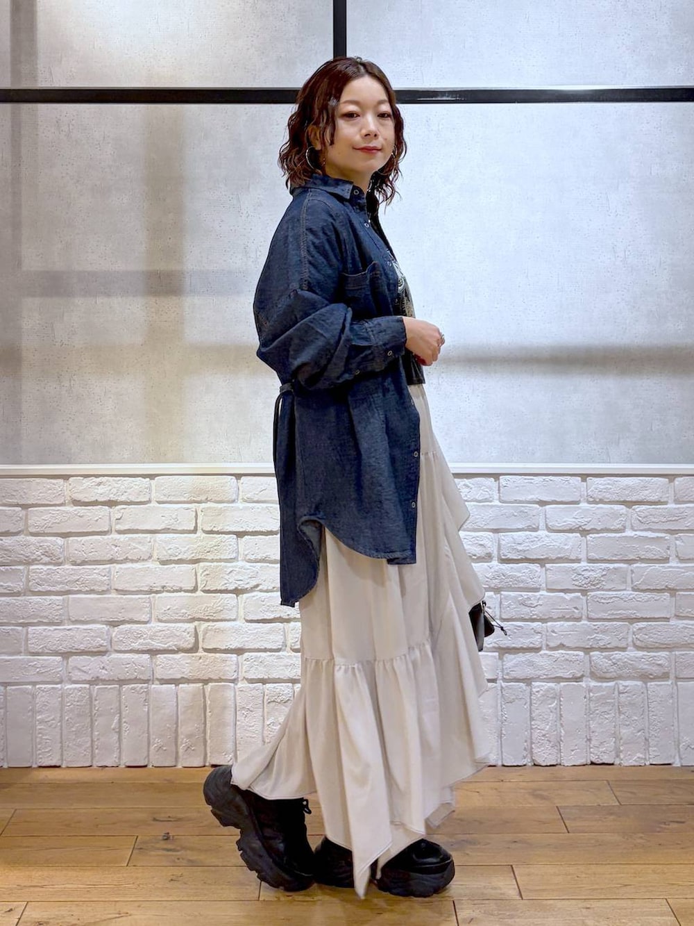 ブラック系のスニーカー、ベージュ系のスカート、ブラック系のボストンバッグを着用したレディースの春コーディネートの7枚目の写真