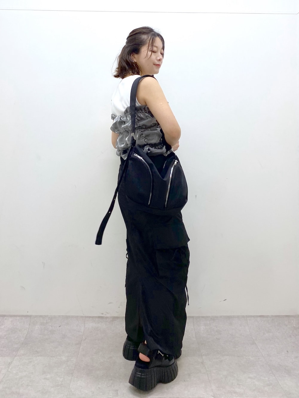 ブラック系のスニーカー、ブラック系のスカート、ブラック系のショルダーバッグを着用したレディースの夏コーディネートの5枚目の写真