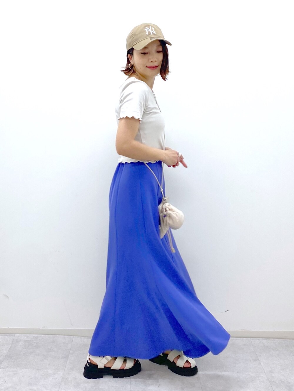 グレー系のトップス、ブルー系のスカート、ベージュ系のショルダーバッグを着用したレディースの夏コーディネートの2枚目の写真