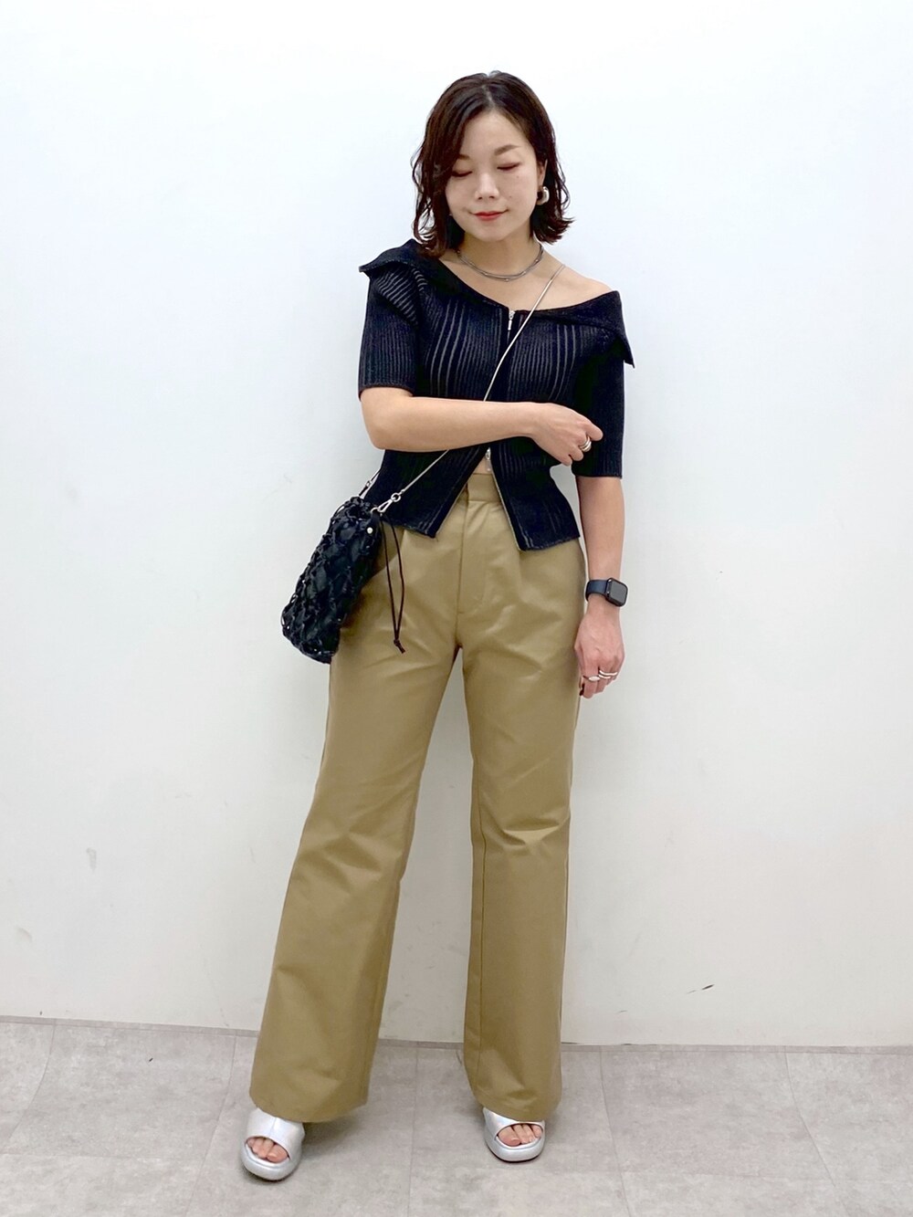 ブラック系のニット/セーター、ベージュ系のチノパンツ、ブラック系のショルダーバッグを着用したレディースの春コーディネートの4枚目の写真