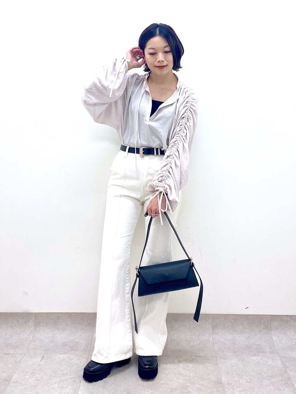 ホワイト系のパンツ、ブラック系のバッグ、ブラック系のローファーを着用したレディースの春コーディネートの5枚目の写真