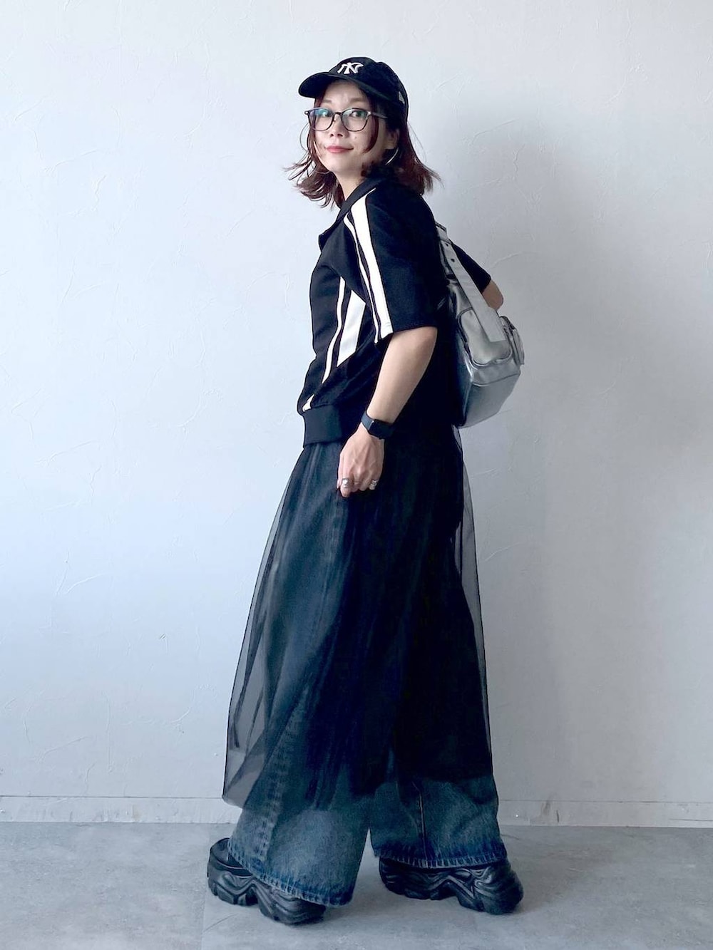 ブラック系のスニーカー、シルバー系のショルダーバッグ、ブルー系のデニムパンツを着用したレディースの夏コーディネートの5枚目の写真