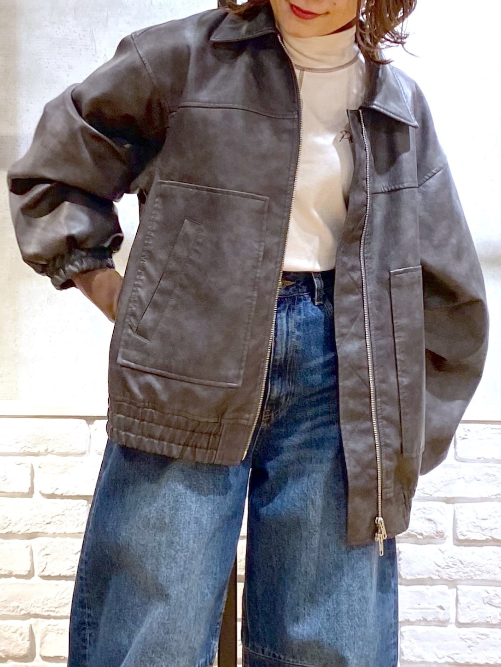 グレー系のブルゾン、ブルー系のデニムパンツ、ブラック系のブーツを着用したレディースの冬コーディネートの2枚目の写真