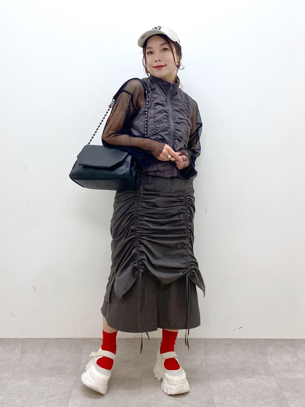 グレー系のスカート、ブラック系のショルダーバッグ、ブラック系のTシャツ/カットソーを着用したレディースの春コーディネートの4枚目の写真