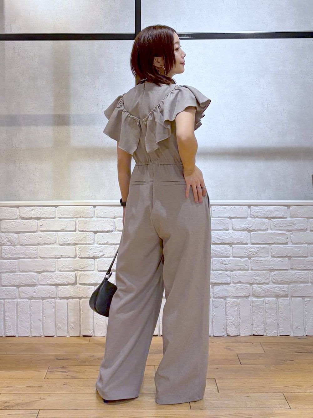 ブラック系のハンドバッグ、ブラック系のサンダル、ベージュ系のサロペット/オーバーオールを着用したレディースの春コーディネートの8枚目の写真