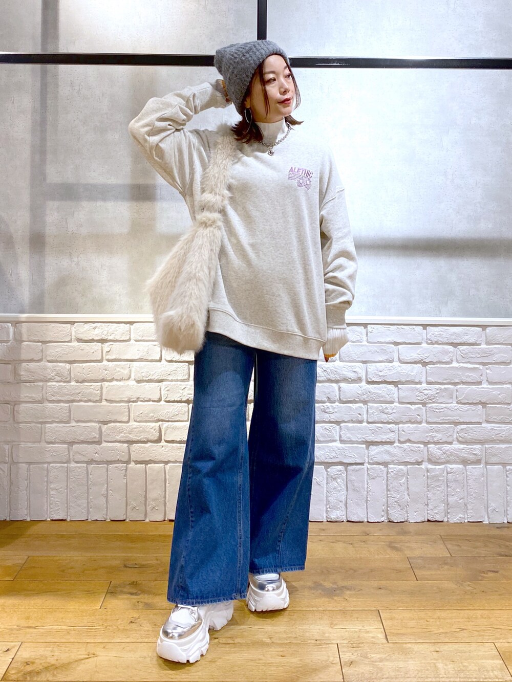 ホワイト系のショルダーバッグ、ブルー系のデニムパンツ、ホワイト系のブーツを着用したレディースの秋コーディネートの4枚目の写真