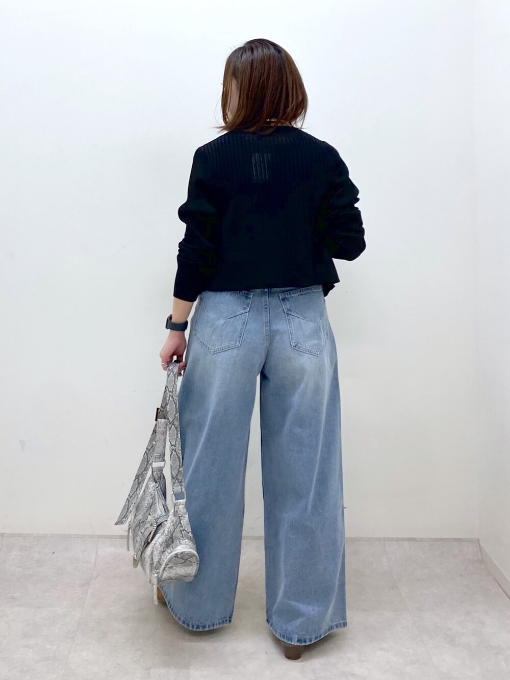 ブラック系のカーディガン/ボレロ、グリーン系のタンクトップ、ブルー系のデニムパンツを着用したレディースの春コーディネートの6枚目の写真