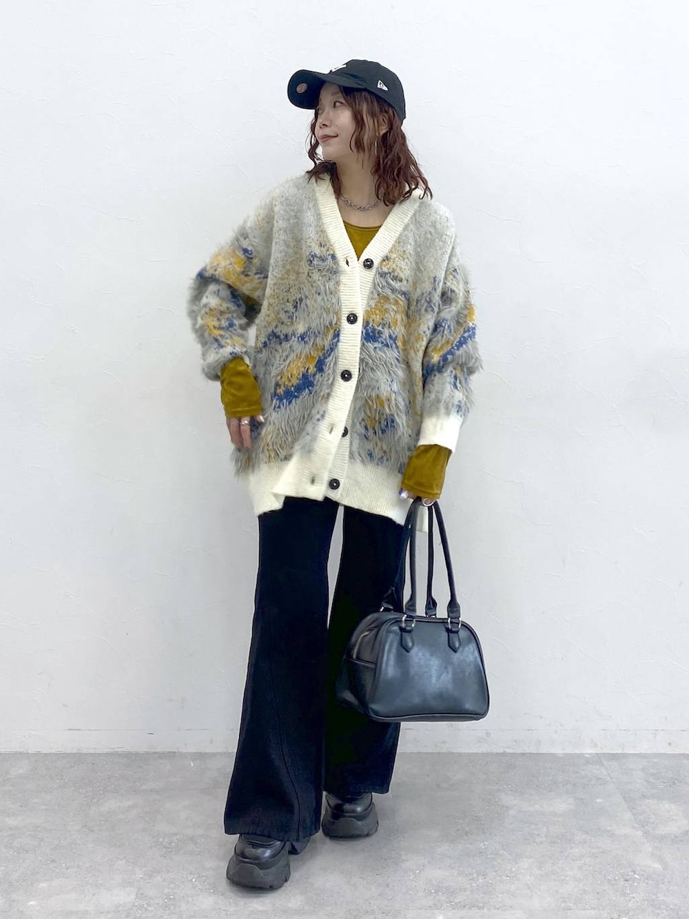 ブラック系のブーツ、ブラック系のボストンバッグ、ホワイト系のカーディガン/ボレロを着用したレディースの秋コーディネートの4枚目の写真