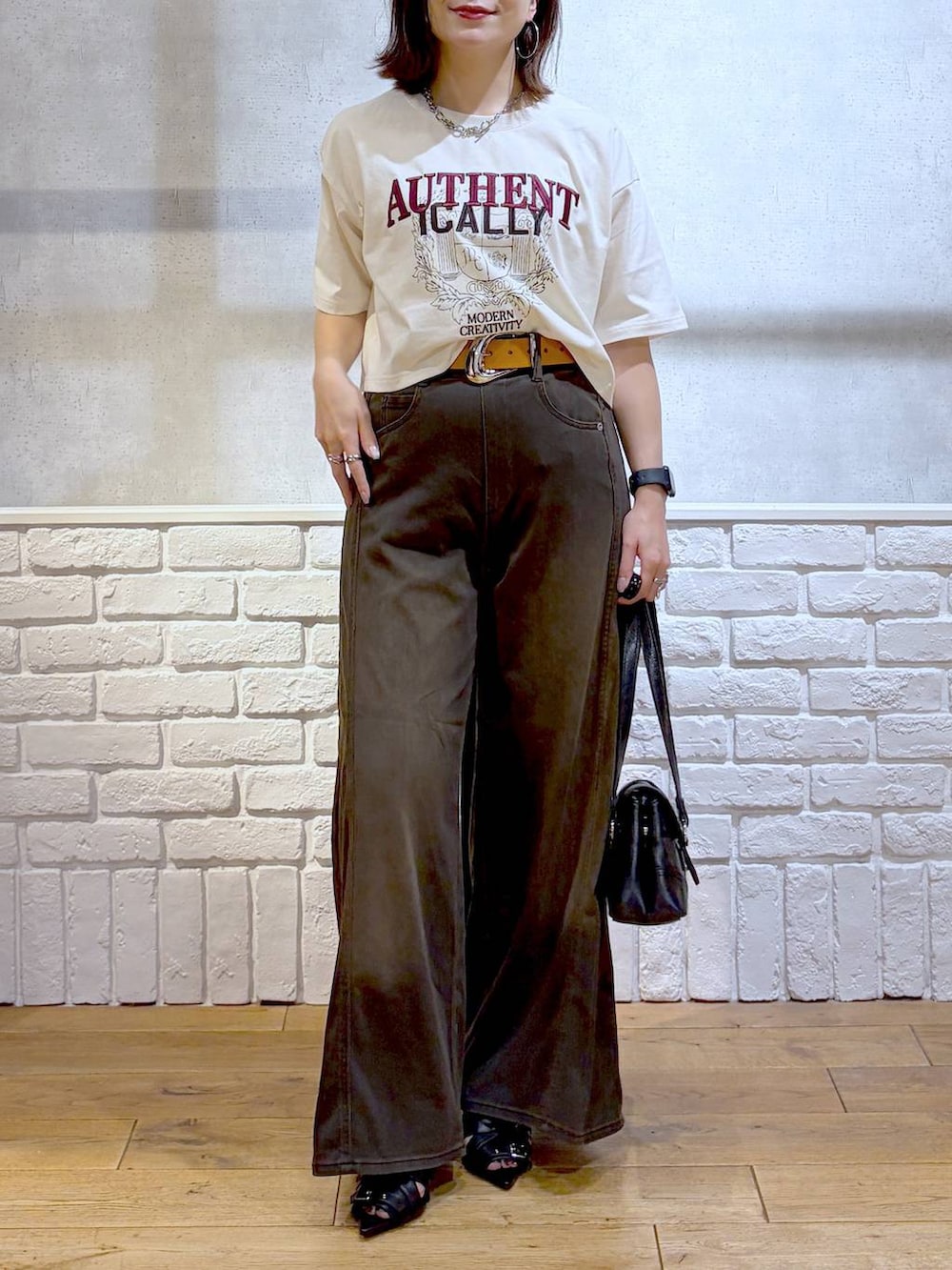 ブラウン系のデニムパンツ、ホワイト系のTシャツ/カットソー、ブラック系のサンダルを着用したレディースの夏コーディネートの3枚目の写真
