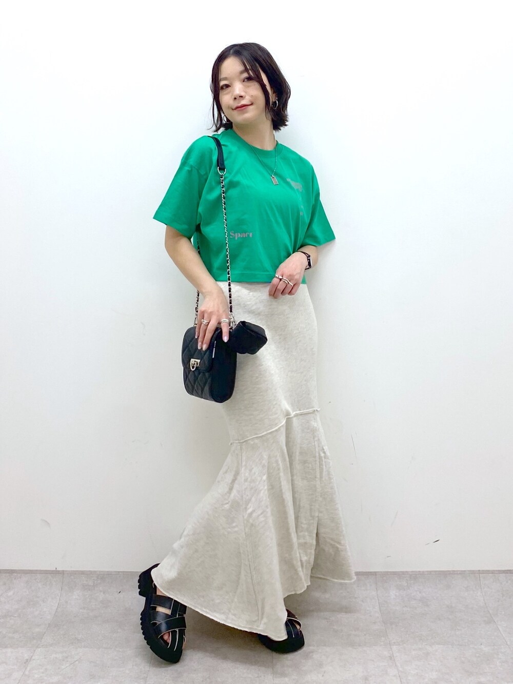 ブラック系のバッグ、ブラック系のサンダル、ベージュ系のスカートを着用したレディースの春コーディネートの2枚目の写真