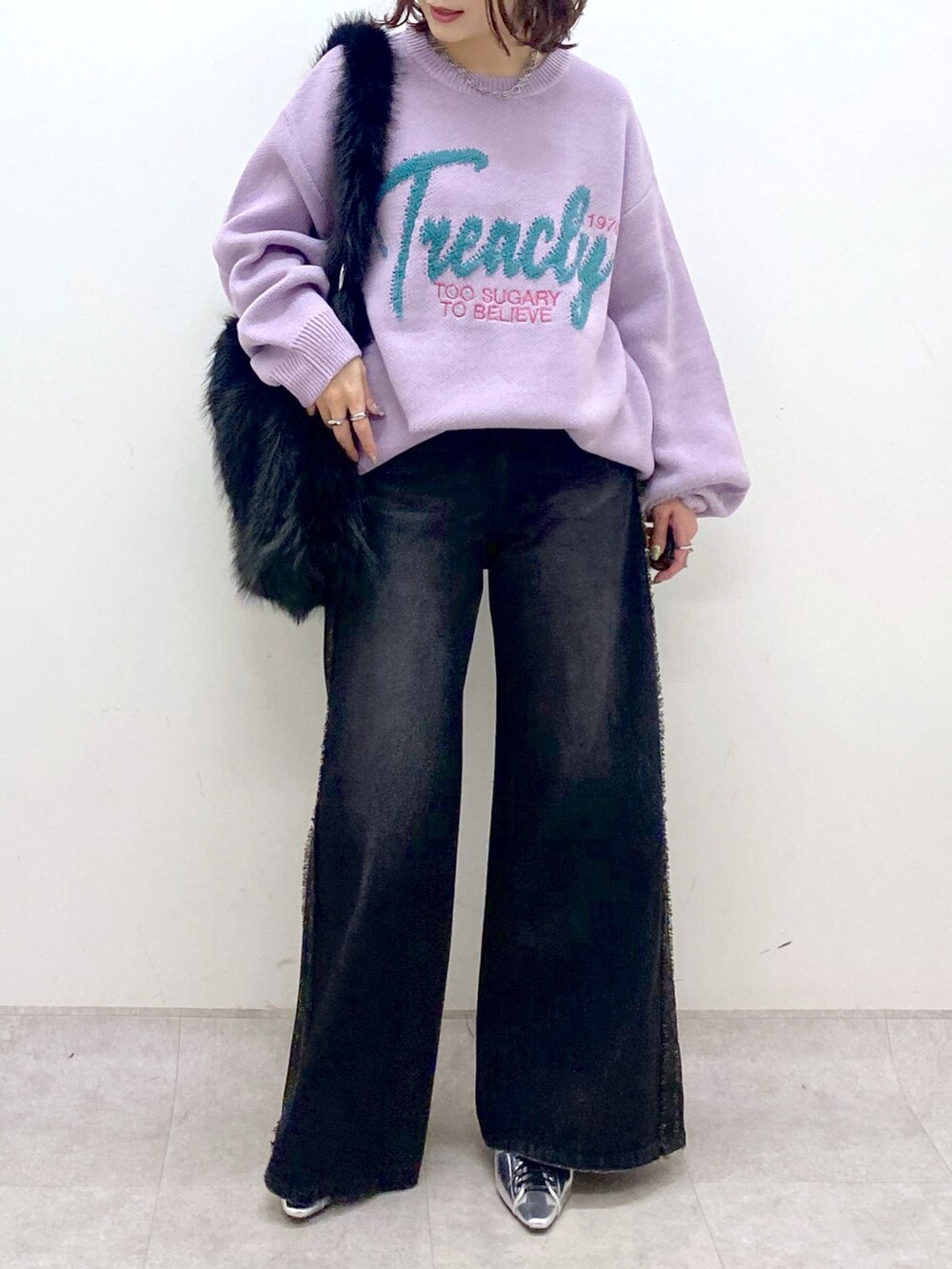パープル系のニット/セーター、ブラック系のデニムパンツ、シルバー系のパンプスを着用したレディースの秋コーディネートの3枚目の写真