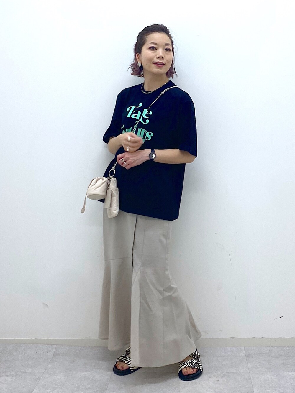 ベージュ系のショルダーバッグ、ベージュ系のスカート、ブラック系のTシャツ/カットソーを着用したレディースの夏コーディネートの2枚目の写真