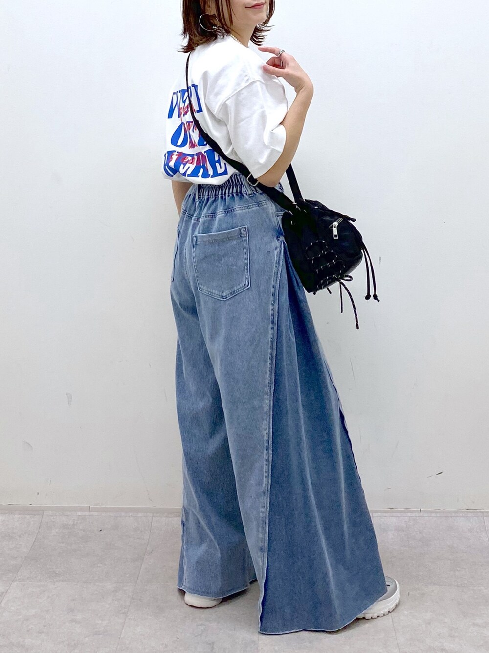 ホワイト系のTシャツ/カットソー、ブラック系のボディバッグ/ウエストポーチ、ブルー系のデニムパンツを着用したレディースの春コーディネートの3枚目の写真