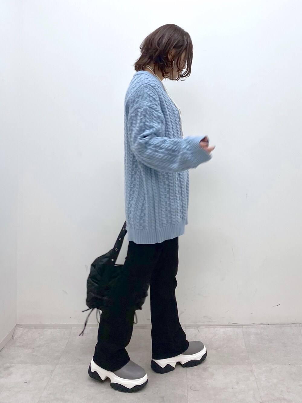 グリーン系のニット/セーター、ブラック系のショルダーバッグ、ブラック系のデニムパンツを着用したレディースの冬コーディネートの6枚目の写真