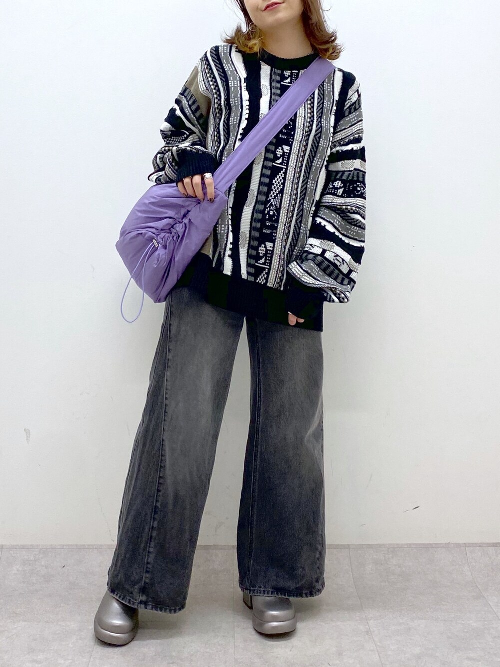ブラック系のニット/セーター、ブラック系のデニムパンツ、パープル系のショルダーバッグを着用したレディースの秋コーディネートの7枚目の写真