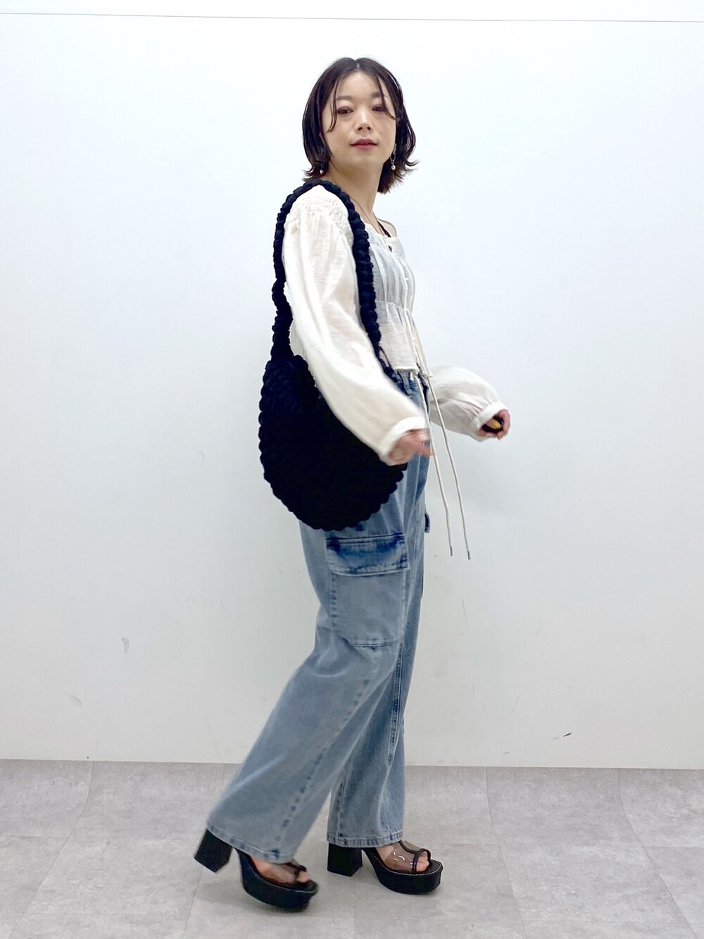 ホワイト系のシャツ/ブラウス、ブルー系のデニムパンツ、ブラック系のバッグを着用したレディースの春コーディネートの4枚目の写真
