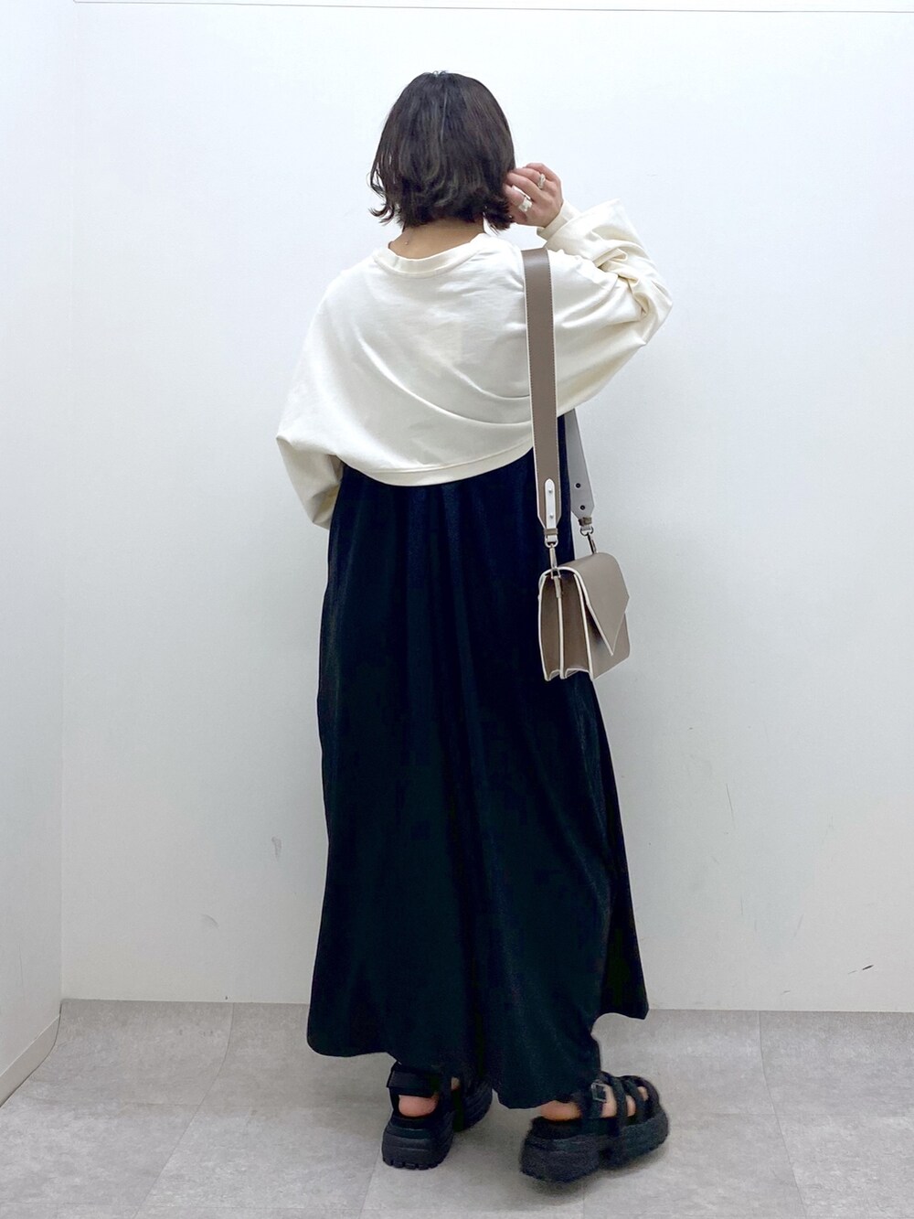 ブラック系のジャンパースカート、ホワイト系のTシャツ/カットソー、ブラウン系のショルダーバッグを着用したレディースの春コーディネートの3枚目の写真