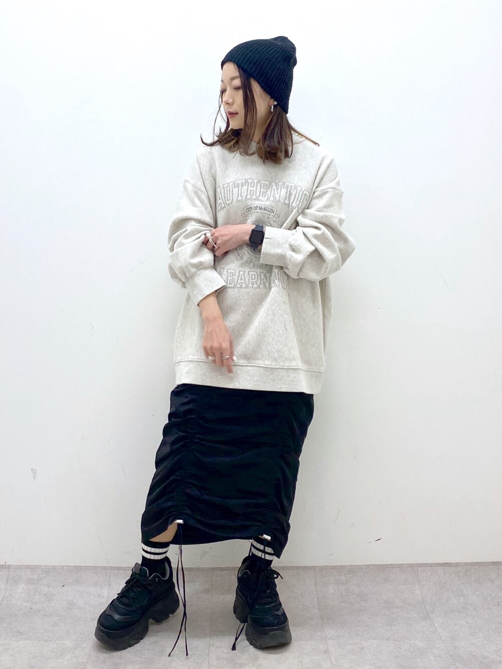 ベージュ系のスウェット、ブラック系のワンピース、ブラック系のスニーカーを着用したレディースの冬コーディネートの7枚目の写真