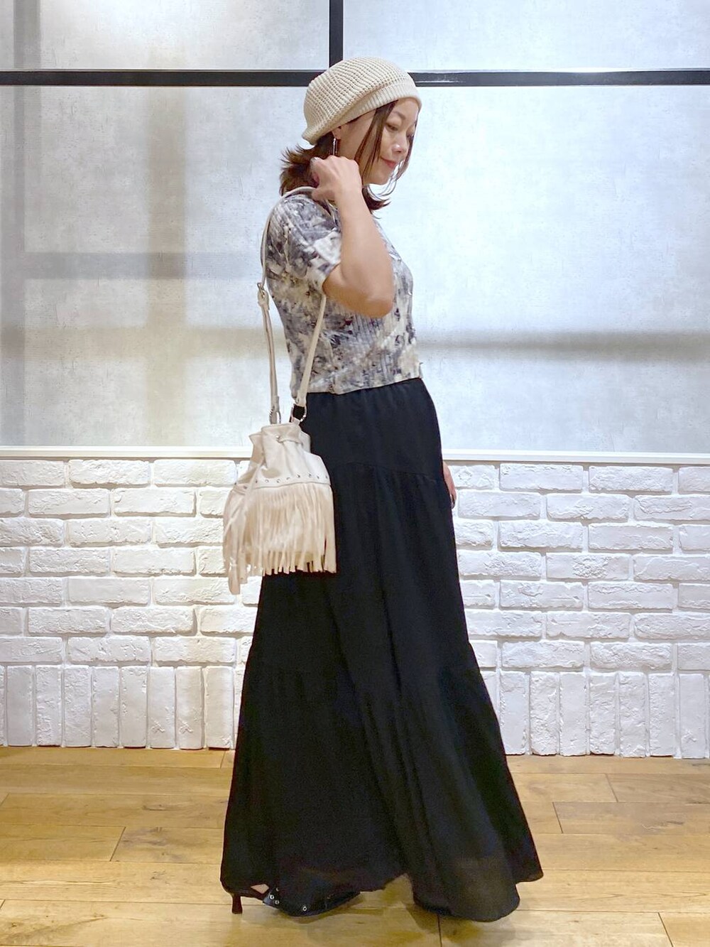 ブラック系のパンプス、ブラック系のスカート、ホワイト系のショルダーバッグを着用したレディースの夏コーディネートの5枚目の写真