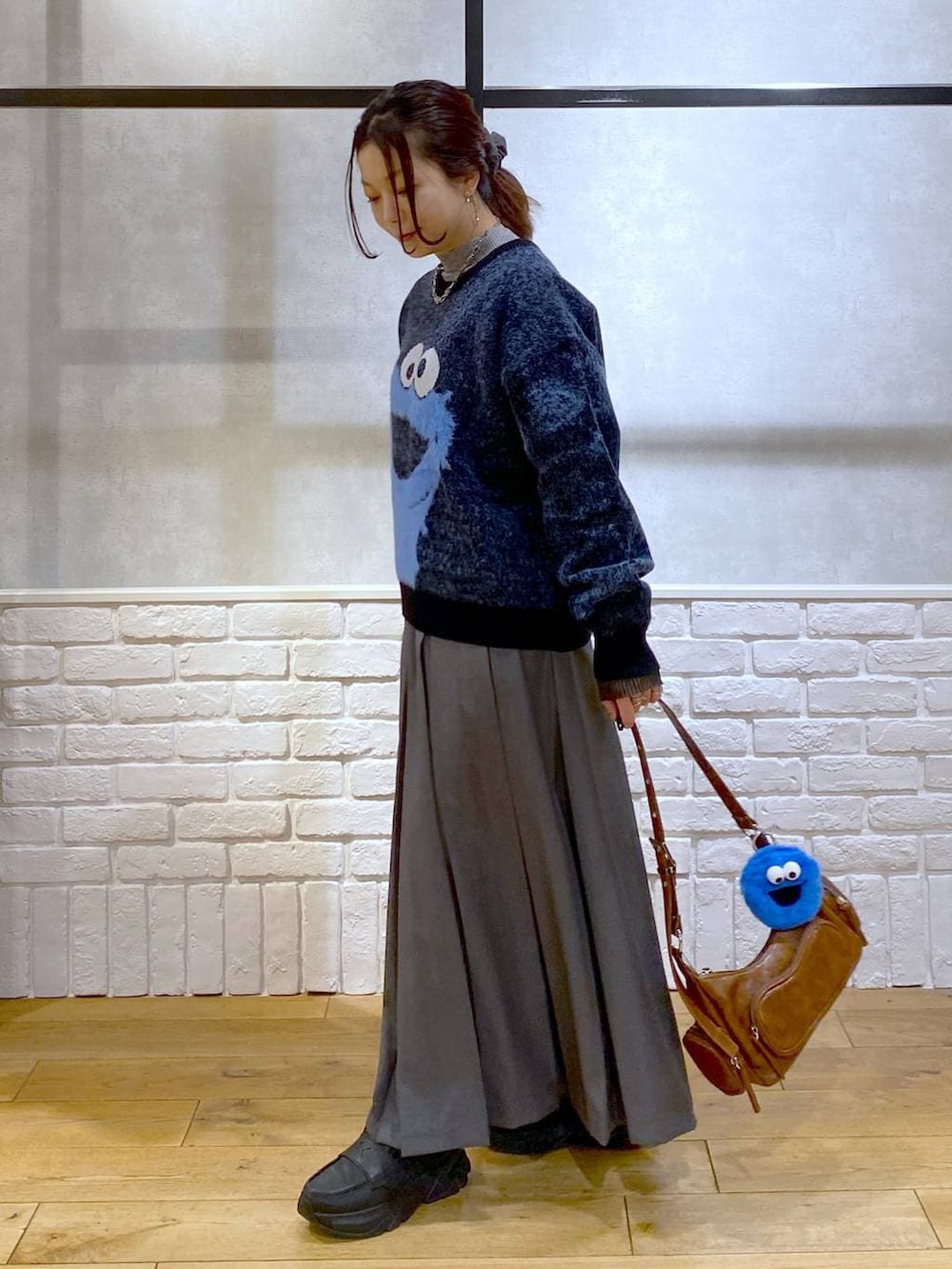 ブラック系のローファー、グレー系のスカート、ブラウン系のショルダーバッグを着用したレディースの冬コーディネートの6枚目の写真