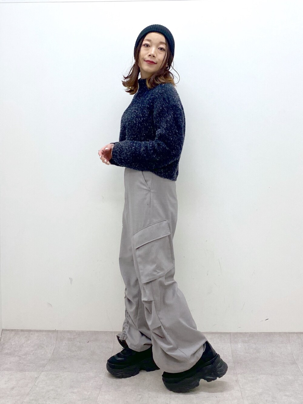 ブラック系のニット/セーター、ベージュ系のその他パンツ、ブラック系のスニーカーを着用したレディースの冬コーディネートの2枚目の写真