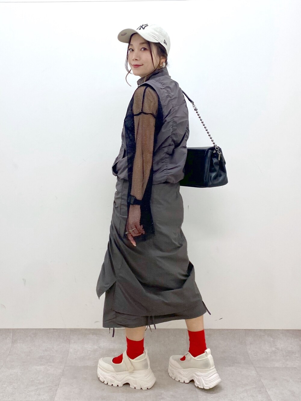 グレー系のスカート、ブラック系のショルダーバッグ、ブラック系のTシャツ/カットソーを着用したレディースの春コーディネートの7枚目の写真