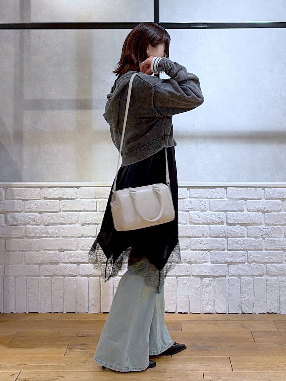 ブルー系のデニムパンツ、ホワイト系のボストンバッグ、ホワイト系のニット/セーターを着用したレディースの春コーディネートの7枚目の写真