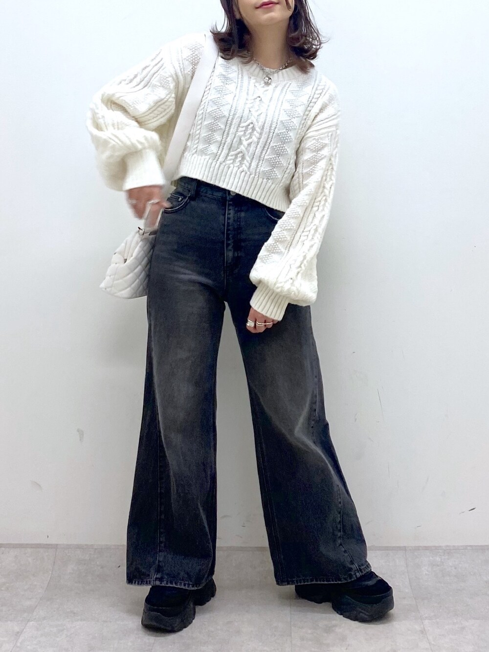 ブラック系のブルゾン、ホワイト系のニット/セーター、ブラック系のデニムパンツを着用したレディースの冬コーディネートの7枚目の写真