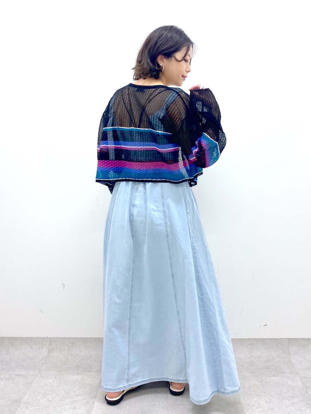 ブルー系のジャンパースカート、ホワイト系のサンダル、ブラック系のカーディガン/ボレロを着用したレディースの春コーディネートの3枚目の写真