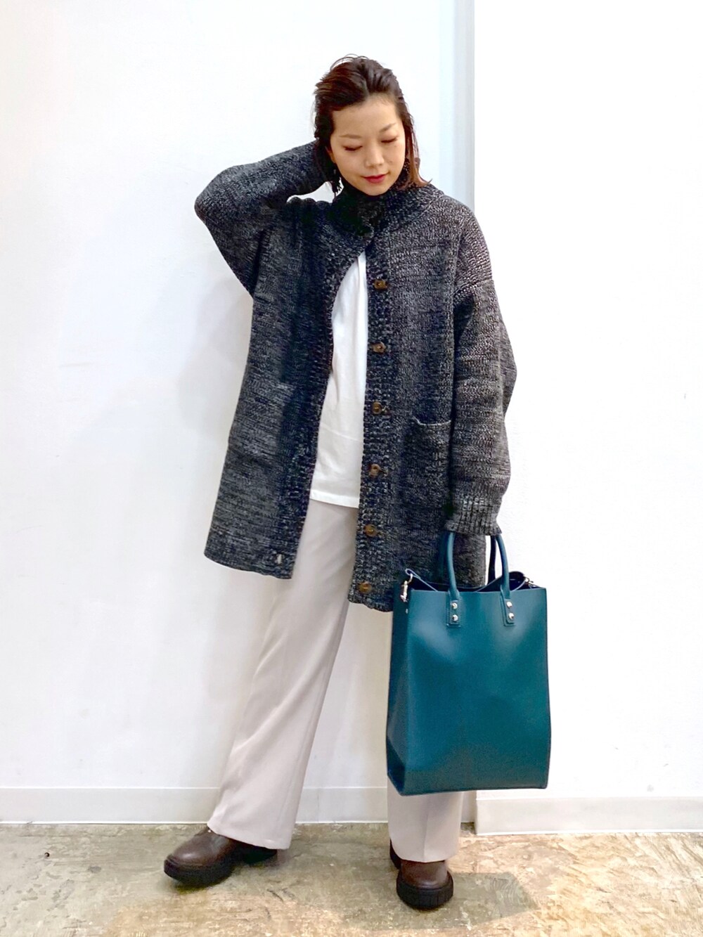 ホワイト系のTシャツ/カットソー、ブラック系のニット/セーター、グリーン系のトートバッグを着用したレディースの冬コーディネートの4枚目の写真