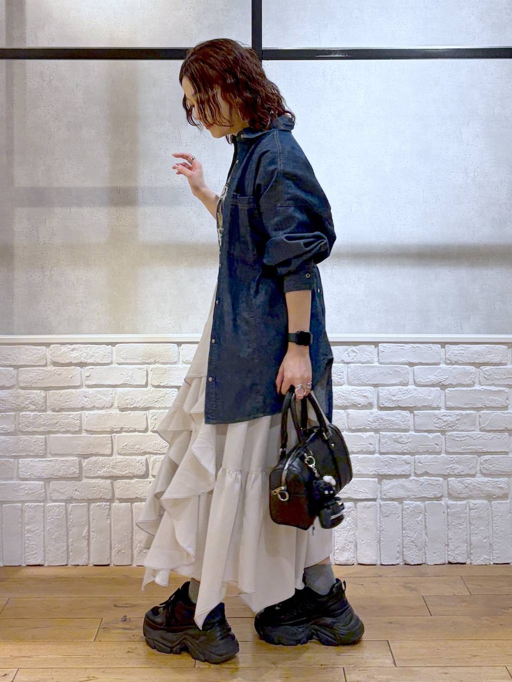 ブラック系のスニーカー、ベージュ系のスカート、ブラック系のボストンバッグを着用したレディースの春コーディネートの5枚目の写真