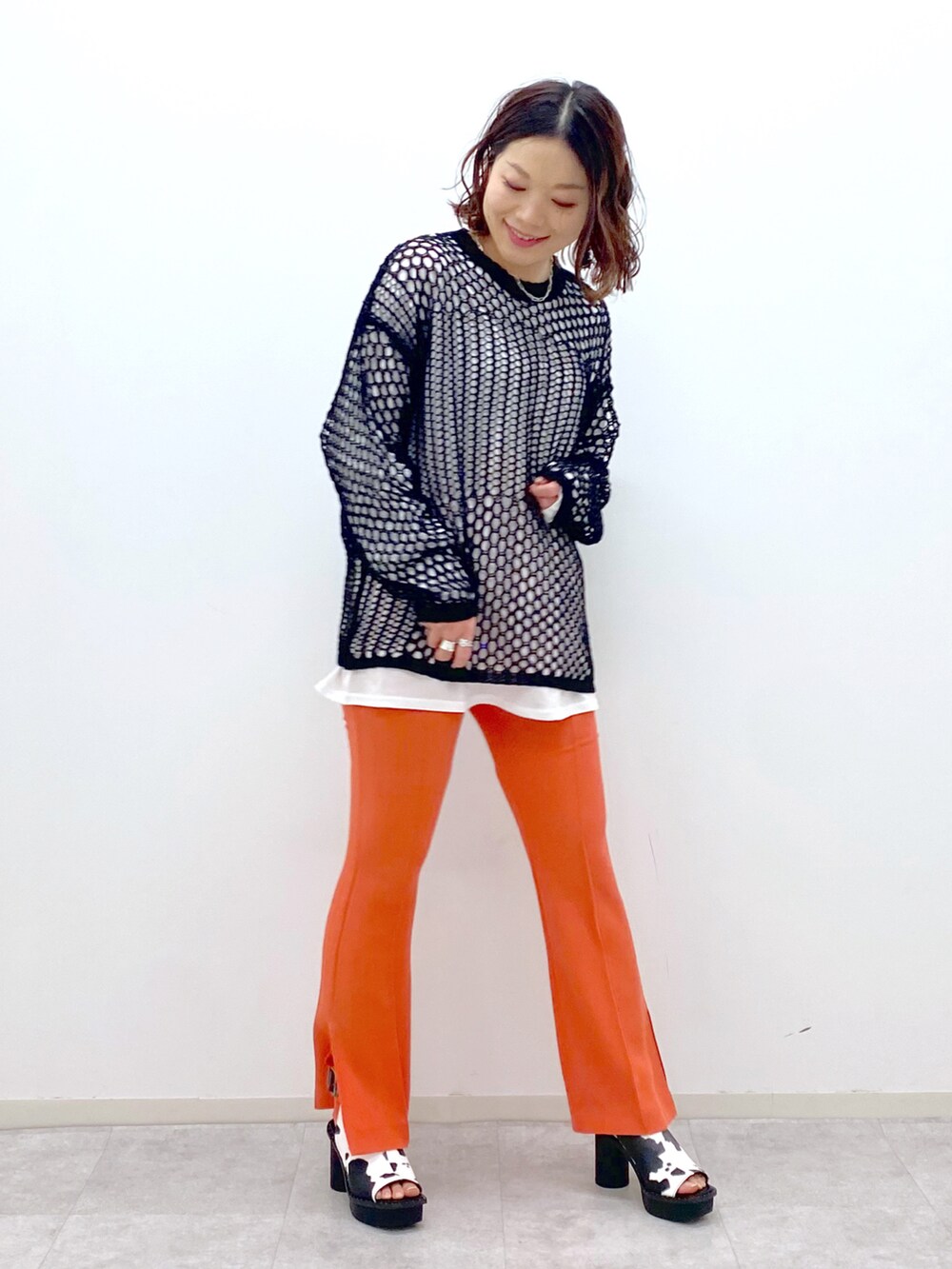 オレンジ系のその他パンツ、ホワイト系のサンダル、ブラック系のニット/セーターを着用したレディースの春コーディネートの2枚目の写真
