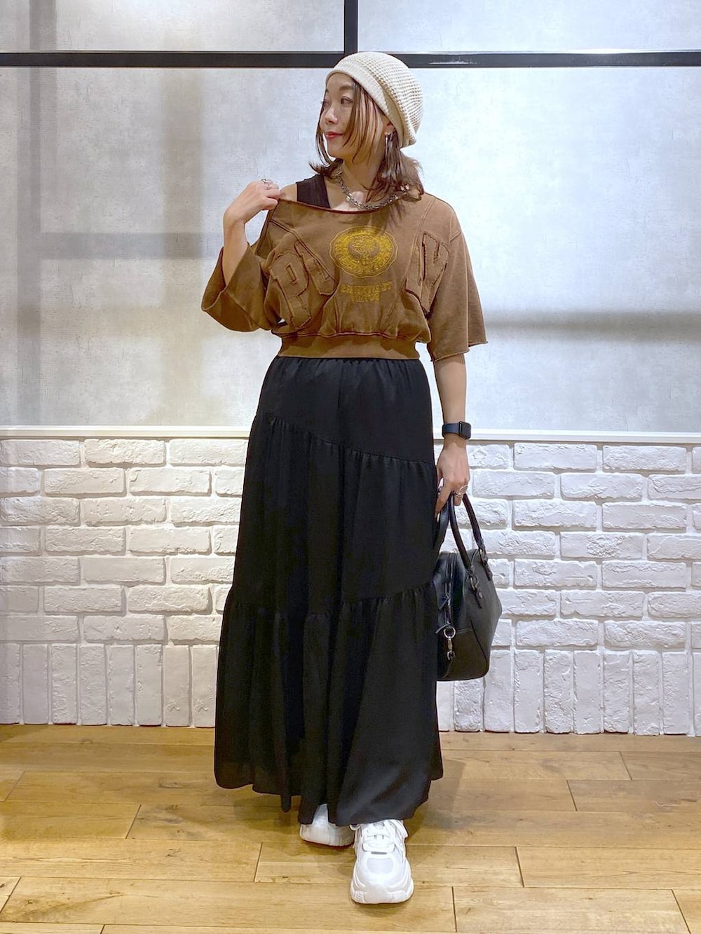 ブラウン系のタンクトップ、ブラック系のショルダーバッグ、ホワイト系のスニーカーを着用したレディースの夏コーディネートの4枚目の写真