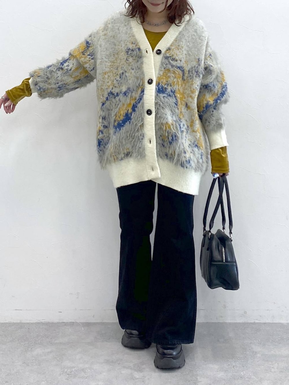 ブラック系のブーツ、ブラック系のボストンバッグ、ホワイト系のカーディガン/ボレロを着用したレディースの秋コーディネートの3枚目の写真