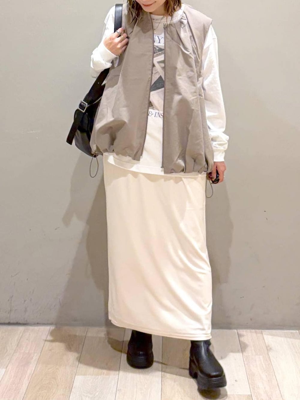 グレー系のベスト、ブラック系のブーツ、ホワイト系のTシャツ/カットソーを着用したレディースの秋コーディネートの3枚目の写真