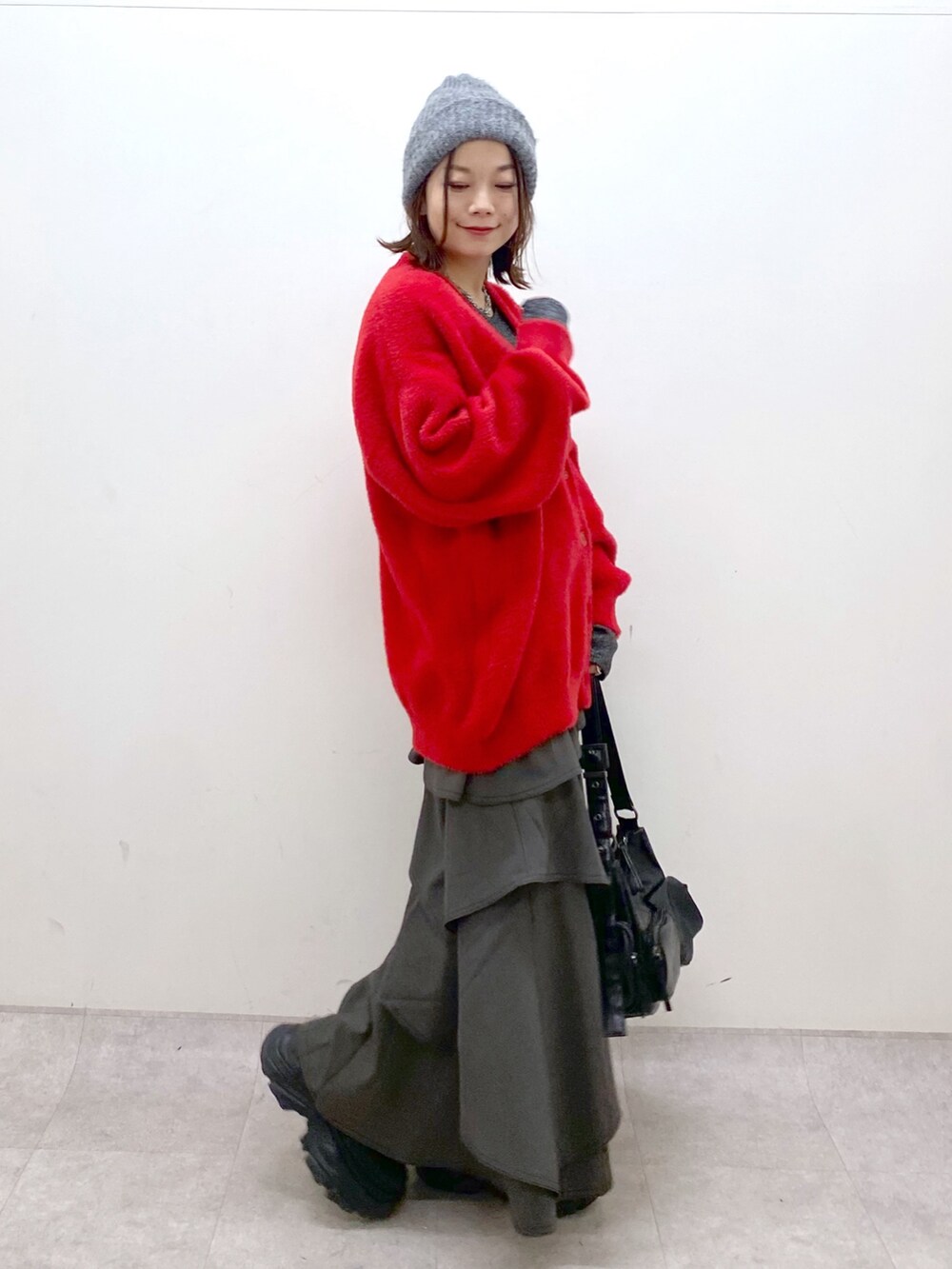 レッド系のカーディガン/ボレロ、シルバー系のTシャツ/カットソー、ブラウン系のスカートを着用したレディースの秋コーディネートの5枚目の写真