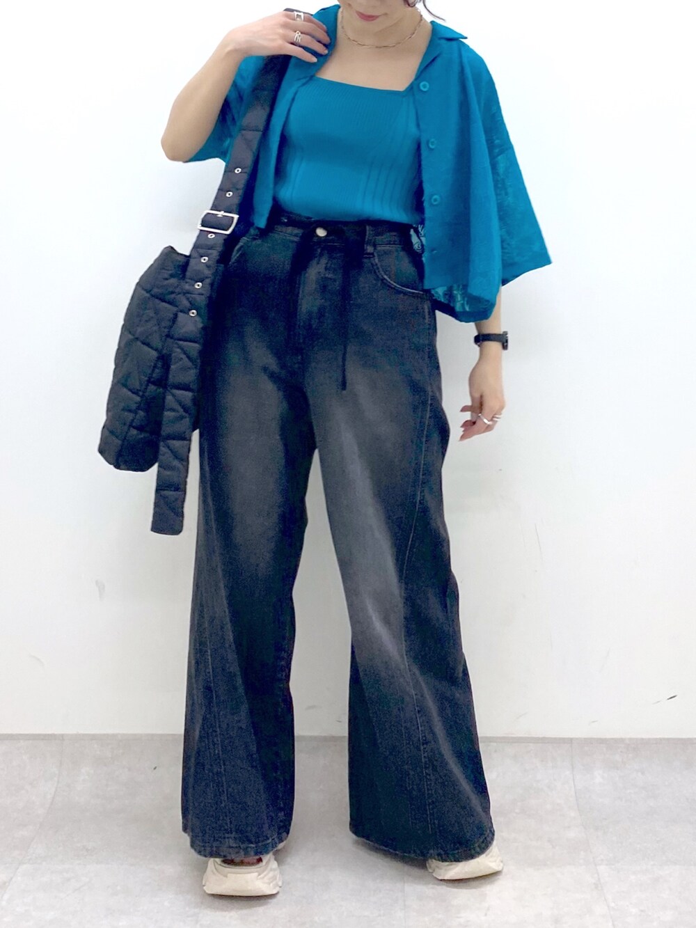 ブラック系のデニムパンツ、ブラック系のショルダーバッグ、ブルー系のタンクトップを着用したレディースの夏コーディネートの5枚目の写真