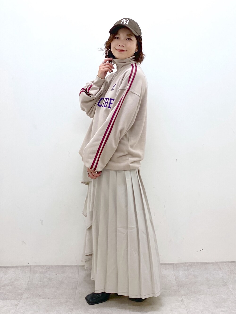 ベージュ系のスウェット、グレー系のスカート、ブラック系のブーツを着用したレディースの秋コーディネートの4枚目の写真