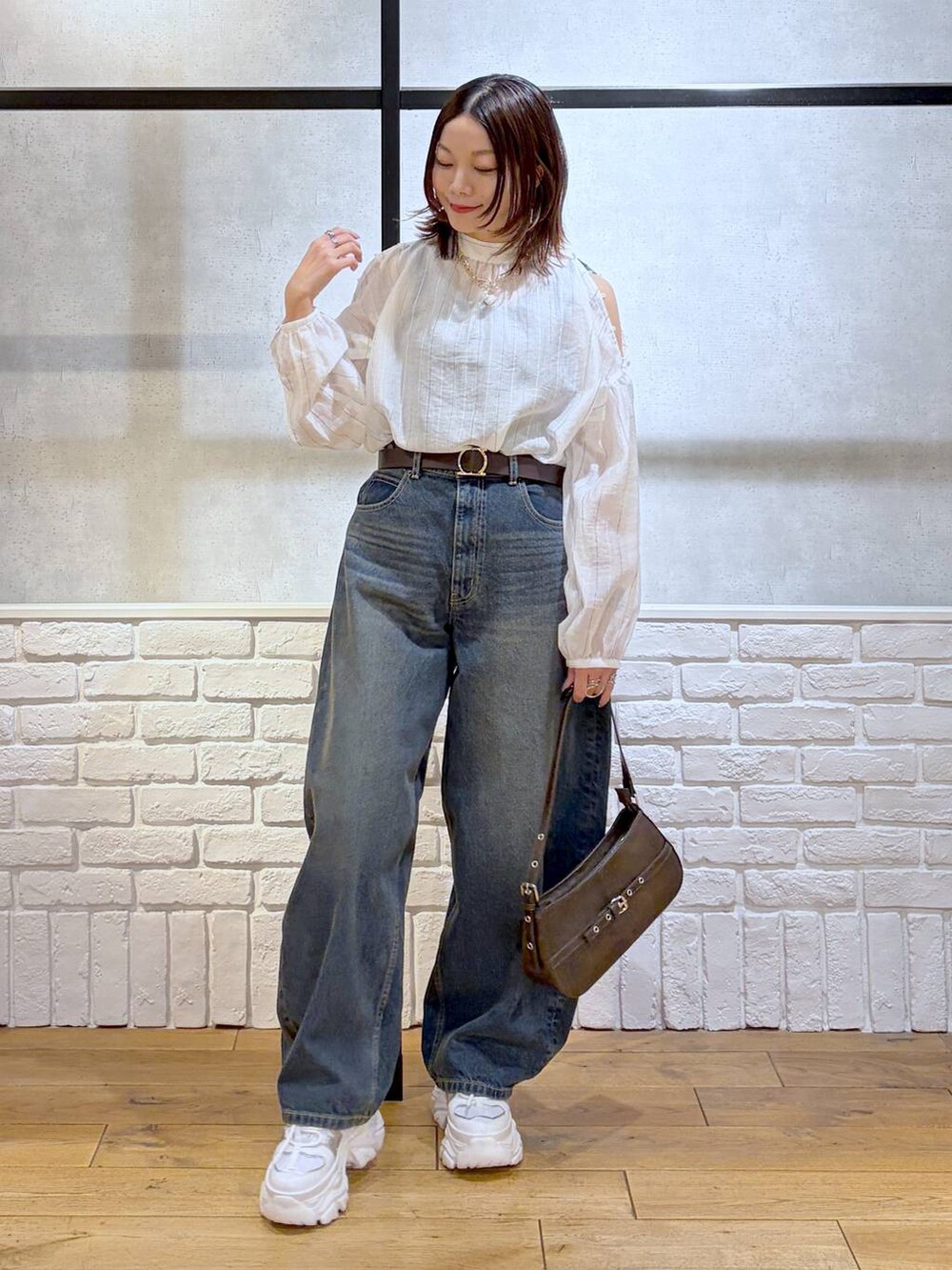 ホワイト系のスニーカー、ブルー系のデニムパンツ、ブラウン系のハンドバッグを着用したレディースの春コーディネートの4枚目の写真