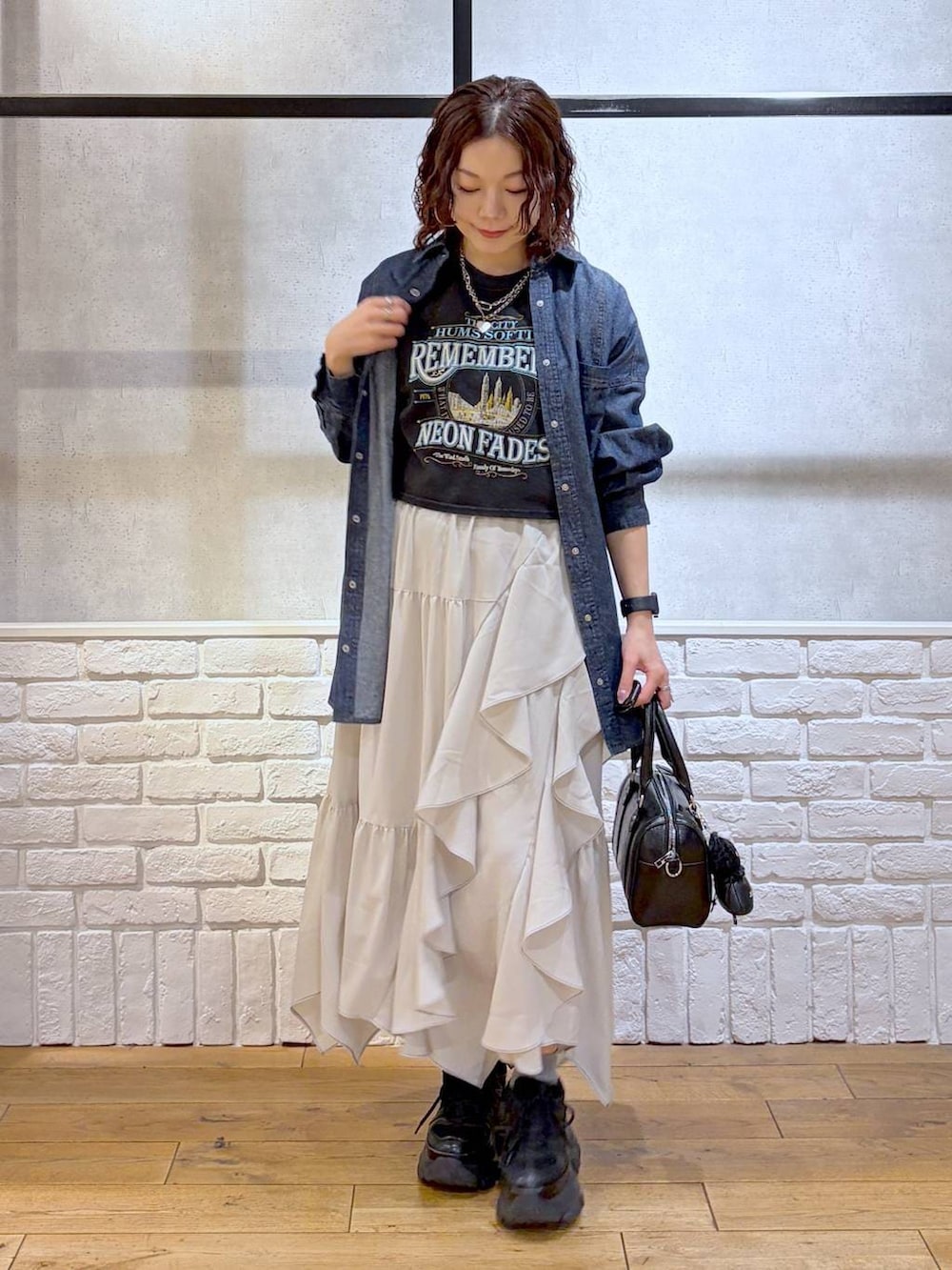 ブラック系のスニーカー、ベージュ系のスカート、ブラック系のボストンバッグを着用したレディースの春コーディネートの8枚目の写真