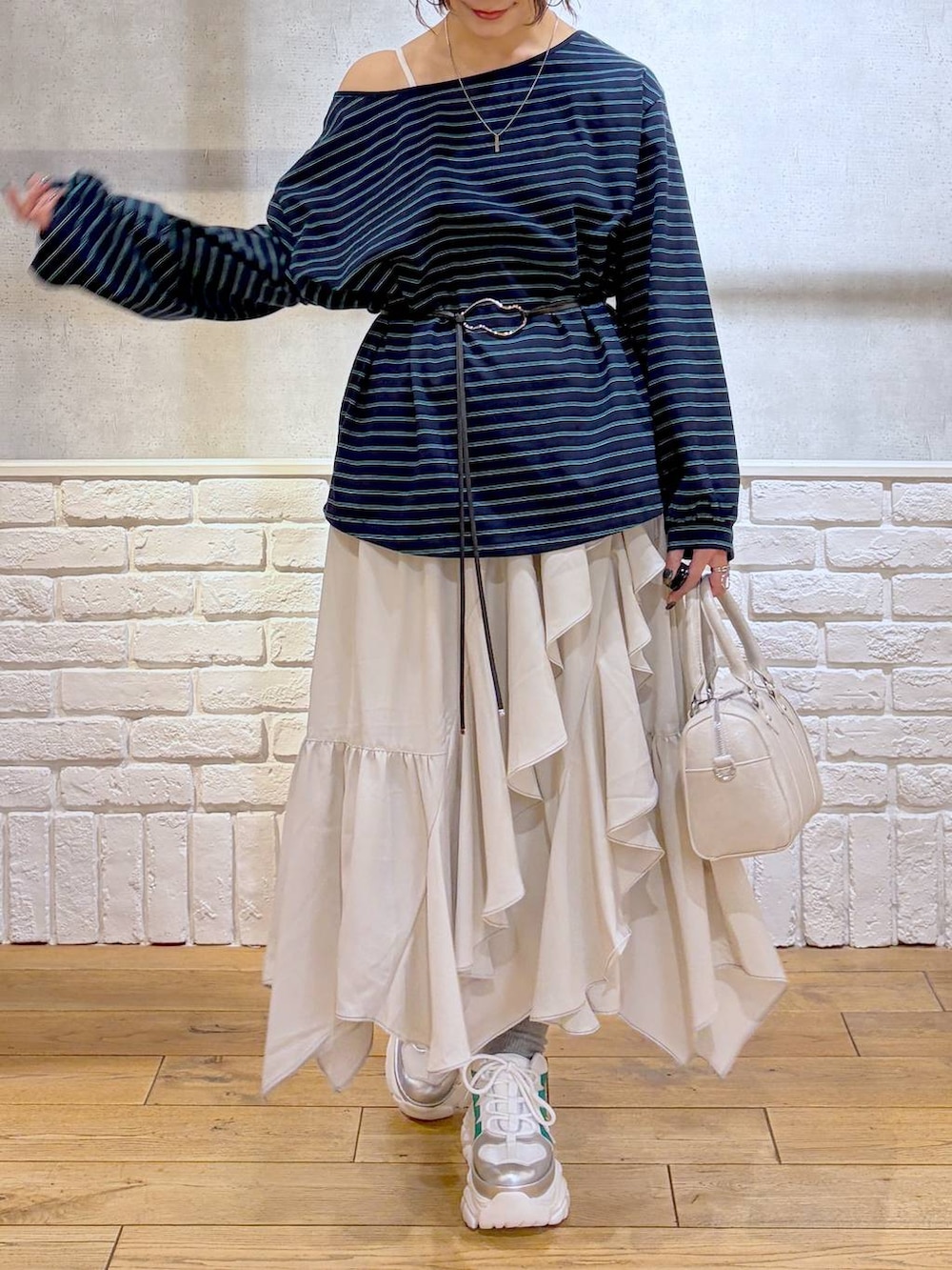 ホワイト系のスニーカー、ベージュ系のスカート、ブラック系のナイロンジャケットを着用したレディースの冬コーディネートの3枚目の写真