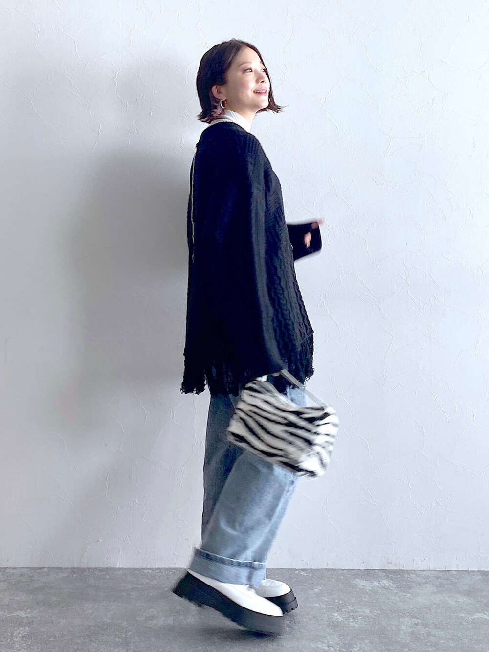 ブラック系のニット/セーター、ブルー系のデニムパンツ、ホワイト系のブーツを着用したレディースの夏コーディネートの3枚目の写真