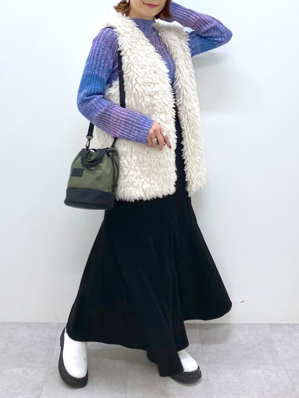 ブラック系のスカート、ホワイト系のシューズ、ブルー系のトップスを着用したレディースの秋コーディネートの5枚目の写真