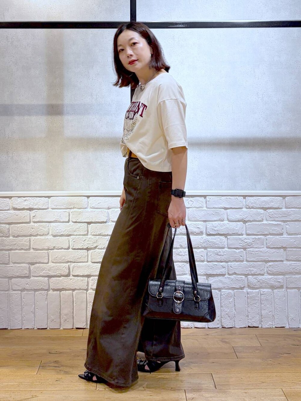 ブラウン系のデニムパンツ、ホワイト系のTシャツ/カットソー、ブラック系のサンダルを着用したレディースの夏コーディネートの8枚目の写真