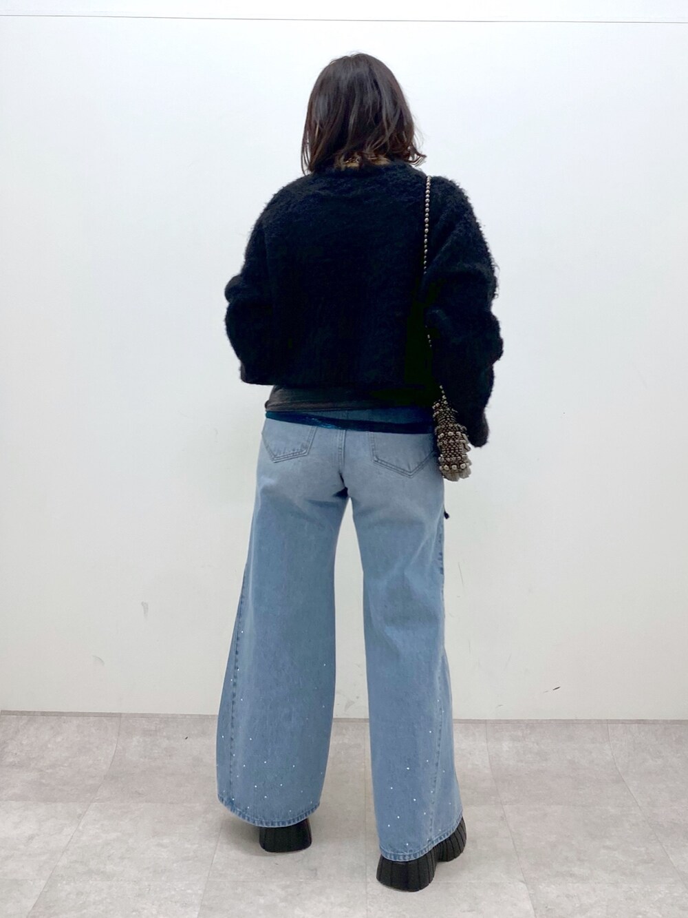ブラック系のニット/セーター、ブルー系のデニムパンツ、ホワイト系のローファーを着用したレディースの冬コーディネートの4枚目の写真