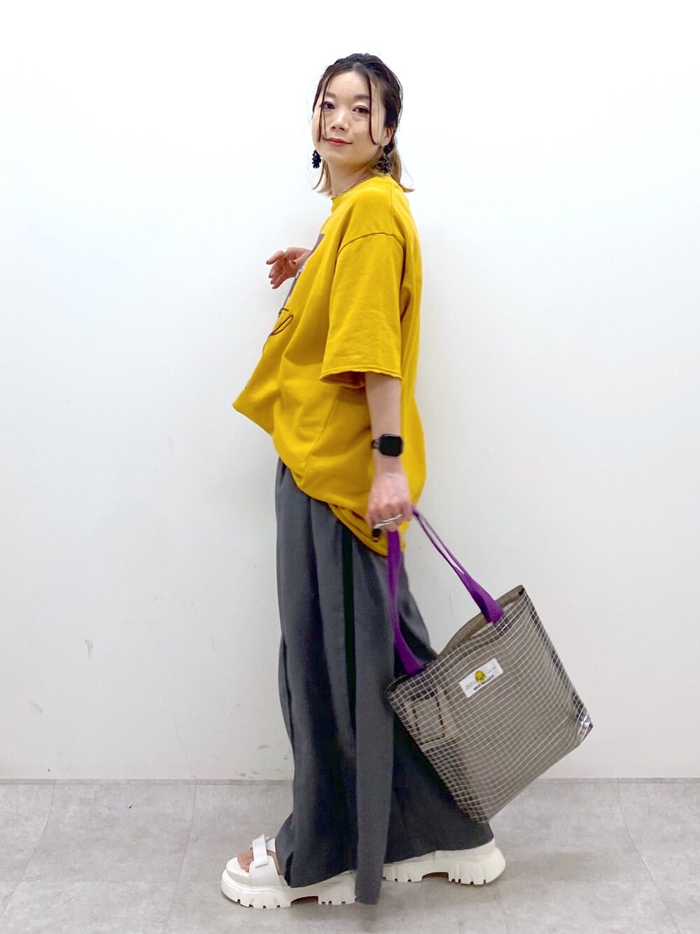 イエロー系のTシャツ/カットソー、グレー系のスラックス、グレー系のトートバッグを着用したレディースの夏コーディネートの3枚目の写真