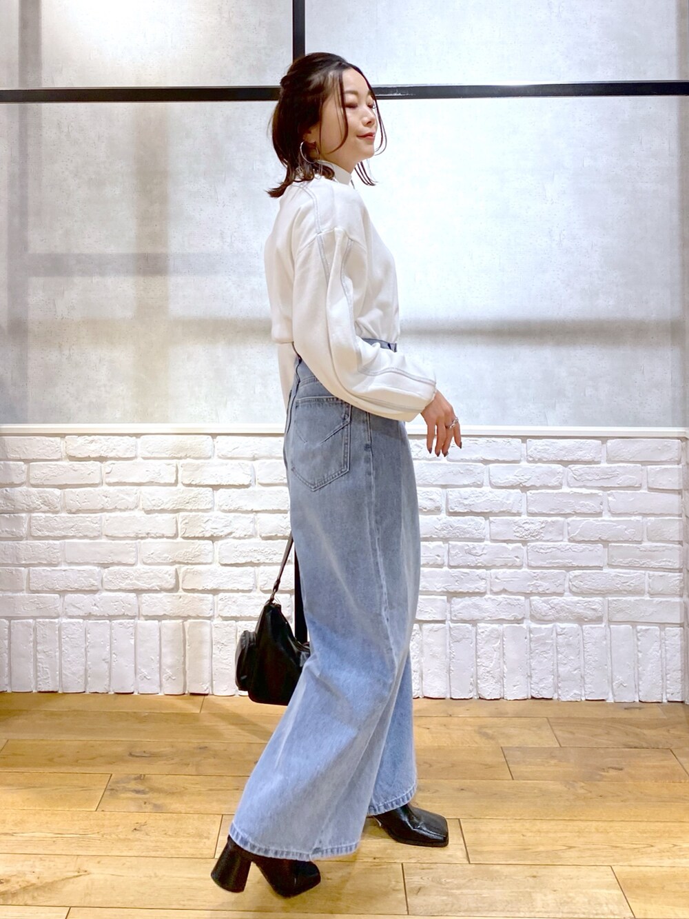 ホワイト系のニット/セーター、ブルー系のデニムパンツ、ブラック系のショルダーバッグを着用したレディースの冬コーディネートの8枚目の写真