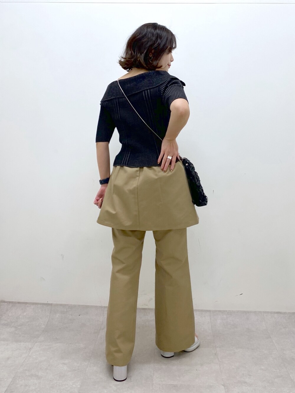 ブラック系のニット/セーター、ベージュ系のチノパンツ、ブラック系のショルダーバッグを着用したレディースの春コーディネートの8枚目の写真