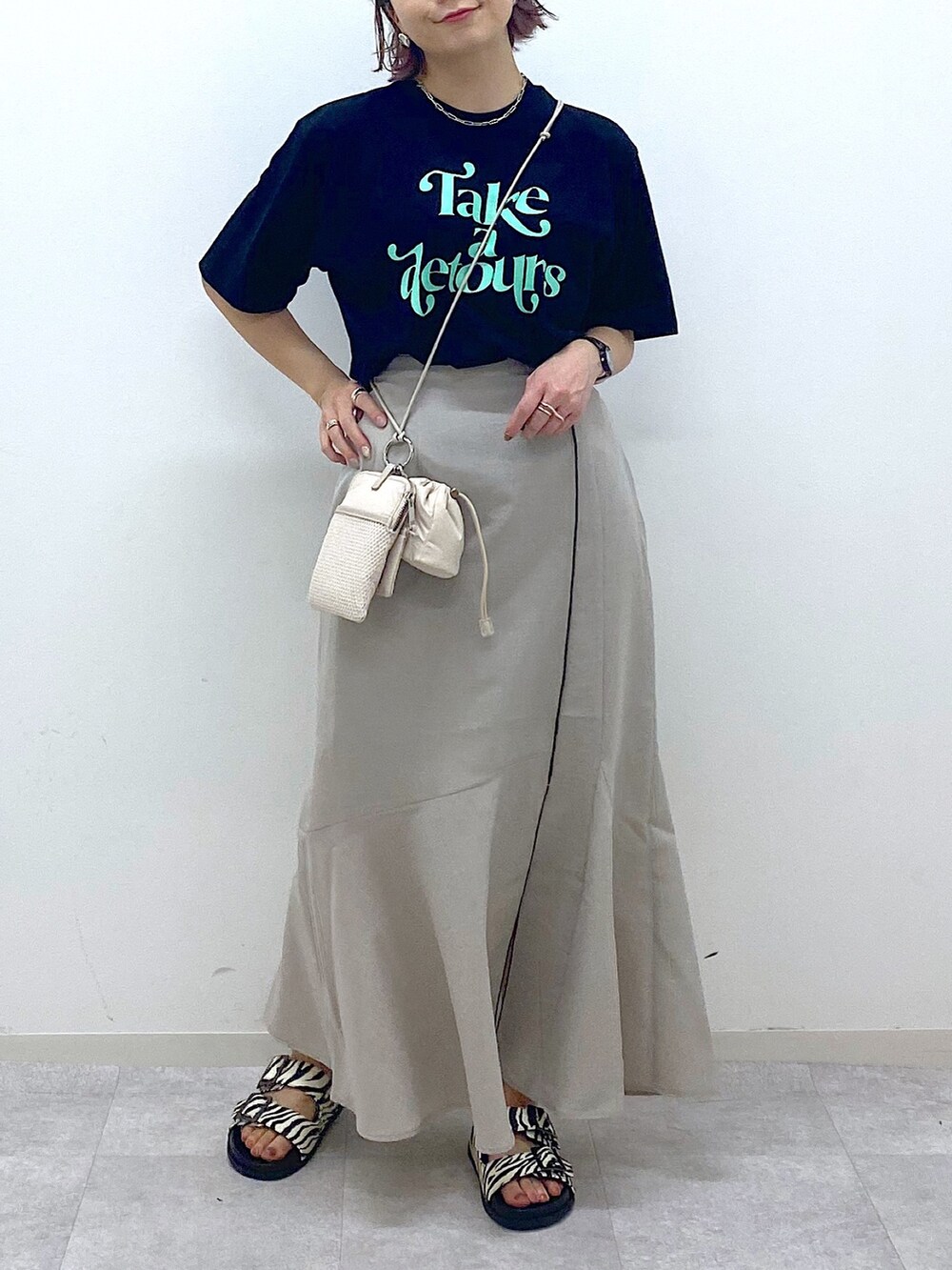 ベージュ系のショルダーバッグ、ベージュ系のスカート、ブラック系のTシャツ/カットソーを着用したレディースの夏コーディネートの4枚目の写真